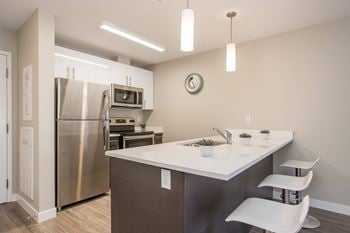 A kitchen with a white counter top and a stainless steel refrigerator.
